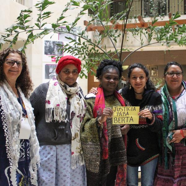 diverse group of women standing in atrium, holding sign Justicia para Berta